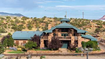 A stone building with a green roof, a balcony, and a view of a mountainous landscape.