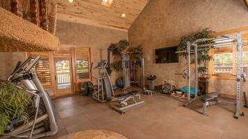 A gym with various exercise equipment, a large window, and a wooden ceiling.
