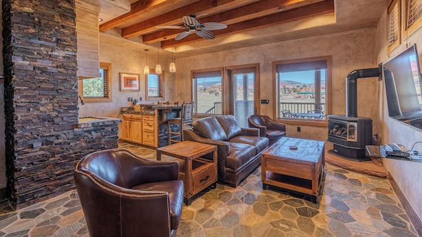A cozy living room with a stone fireplace, leather furniture, and a stone floor.