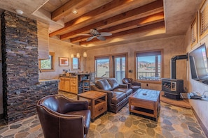 A cozy living room with a stone fireplace, leather furniture, and a stone floor.