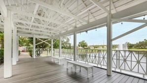 Un espace extérieur abrité, doté de bancs, d’une terrasse en bois et offrant une vue sur une étendue d’eau.