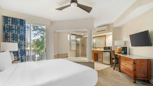 Une chambre d’hôtel avec un grand lit, un bureau avec une chaise, une télévision et une salle de bain équipée d’un lavabo et d’une douche.