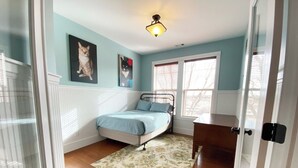Quarto com cama, escrivaninha, janela com persianas e luminária no teto.