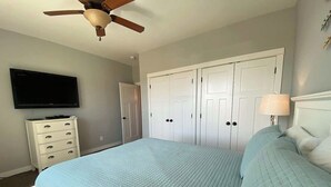 A bedroom with a bed, a dresser, a television, a ceiling fan, and a wardrobe. - Midnight Manor, Kanab: red rock views, pet-ready (Kanab)