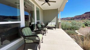 A covered porch with wicker furniture, a ceiling fan, and a view of a desert landscape. - Midnight Manor, Kanab: red rock views, pet-ready (Kanab)