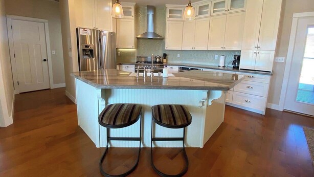 A modern kitchen with a central island, stainless steel appliances, and pendant lighting. - Midnight Manor, Kanab: red rock views, pet-ready (Kanab)