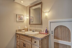 Bathroom features a granite countertop, white sink, and wooden cabinets with dark handles.