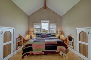 Cozy loft-style room with a high ceiling, central bed, and bookshelves on either side.