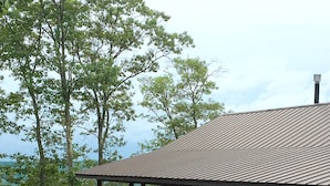 Een chalet met een veranda, omgeven door bomen en een grindpad.