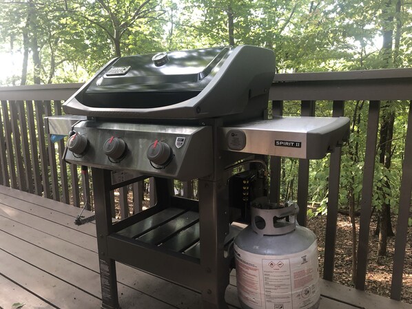 A barbecue grill with a propane tank on a wooden deck.