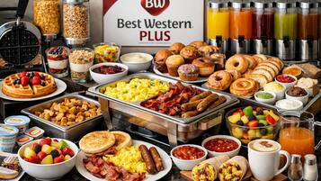 Buffet com diversas opções de café da manhã, incluindo waffles, ovos mexidos, salsichas e doces.