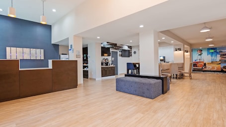 A spacious lobby with a reception desk, a seating area, and a kitchen visible in the background.