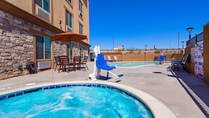 A pool area with a hot tub, lounge chairs, and a stone building. - Best Western Plus New Barstow Inn & Suites (Barstow)
