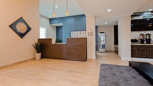A reception area with a wooden reception desk, a potted plant, and a framed artwork on the wall. - Best Western Plus New Barstow Inn & Suites (Barstow)