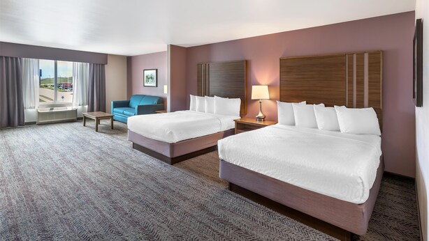 A hotel room with two beds, a sofa, a small table, and a window with a view of the outside. - Best Western Plus Rapid City Rushmore (Rapid City)