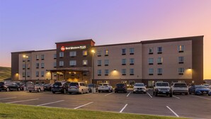 A hotel with a 'Best Western PLUS' sign, multiple parking spaces, and a flat-roofed structure. - Best Western Plus Rapid City Rushmore (Rapid City)