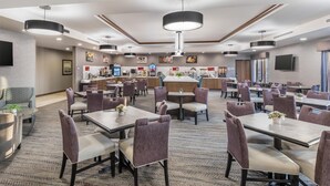 A hotel lobby with multiple dining tables and chairs, a reception area, and a TV mounted on the wall. - Best Western Plus Rapid City Rushmore (Rapid City)