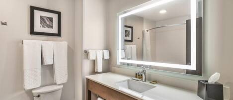 Un baño moderno con un lavabo blanco, un espejo grande y un inodoro.