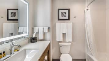 A modern bathroom with a large mirror, white sink, and a shower with a curtain.