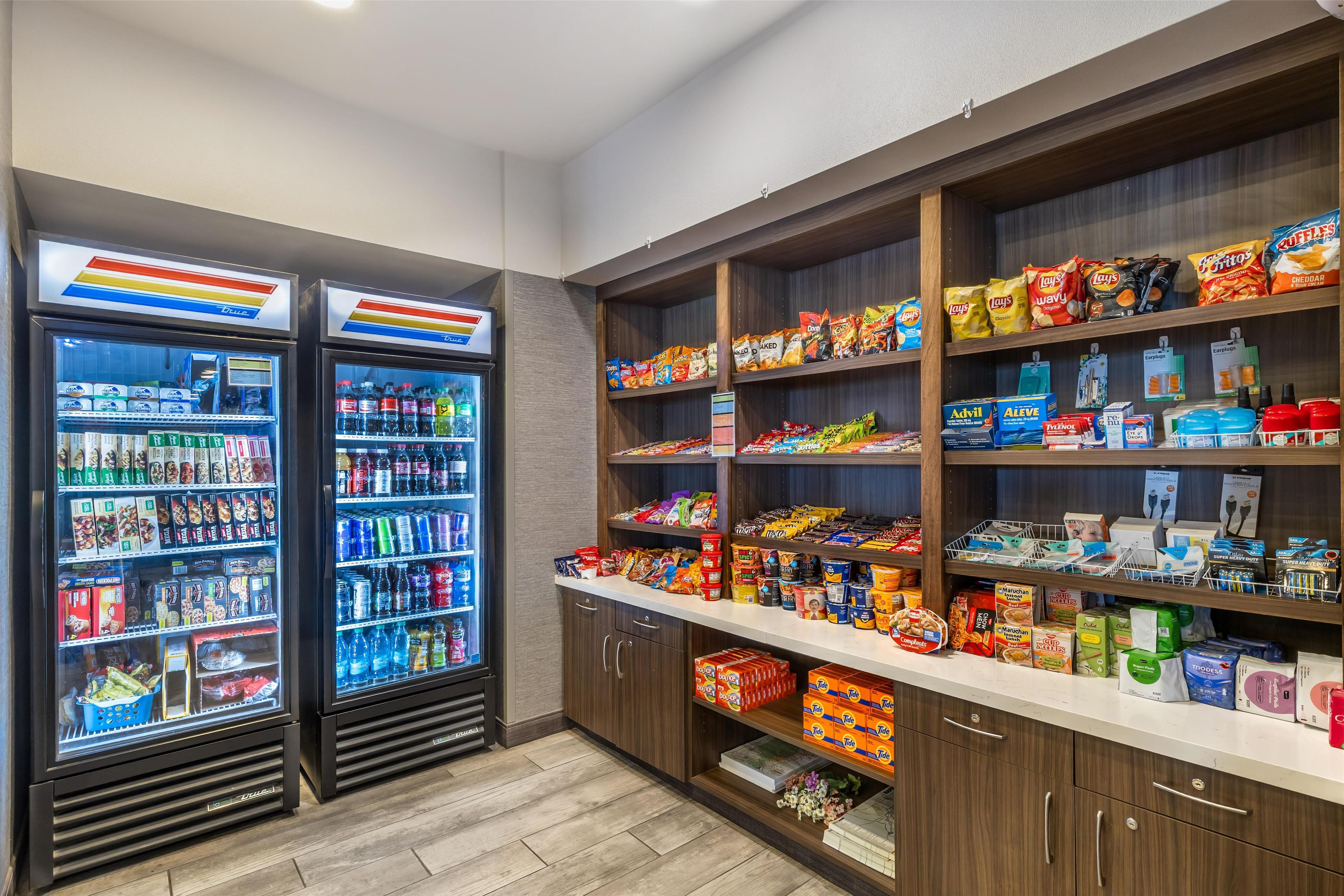 Un kiosque en libre-service proposant des collations et des boissons, équipé de distributeurs de boissons réfrigérés et d’étagères remplies de collations et de boissons.
