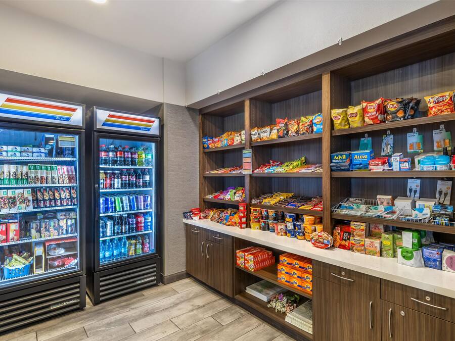 A self-service snack and beverage kiosk with refrigerated drink dispensers and shelves stocked with snacks and beverages.