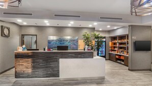A reception area with a wooden reception desk, a large painting on the wall, a clock, and a vending machine. - Best Western Plus Rapid City Rushmore (Rapid City)