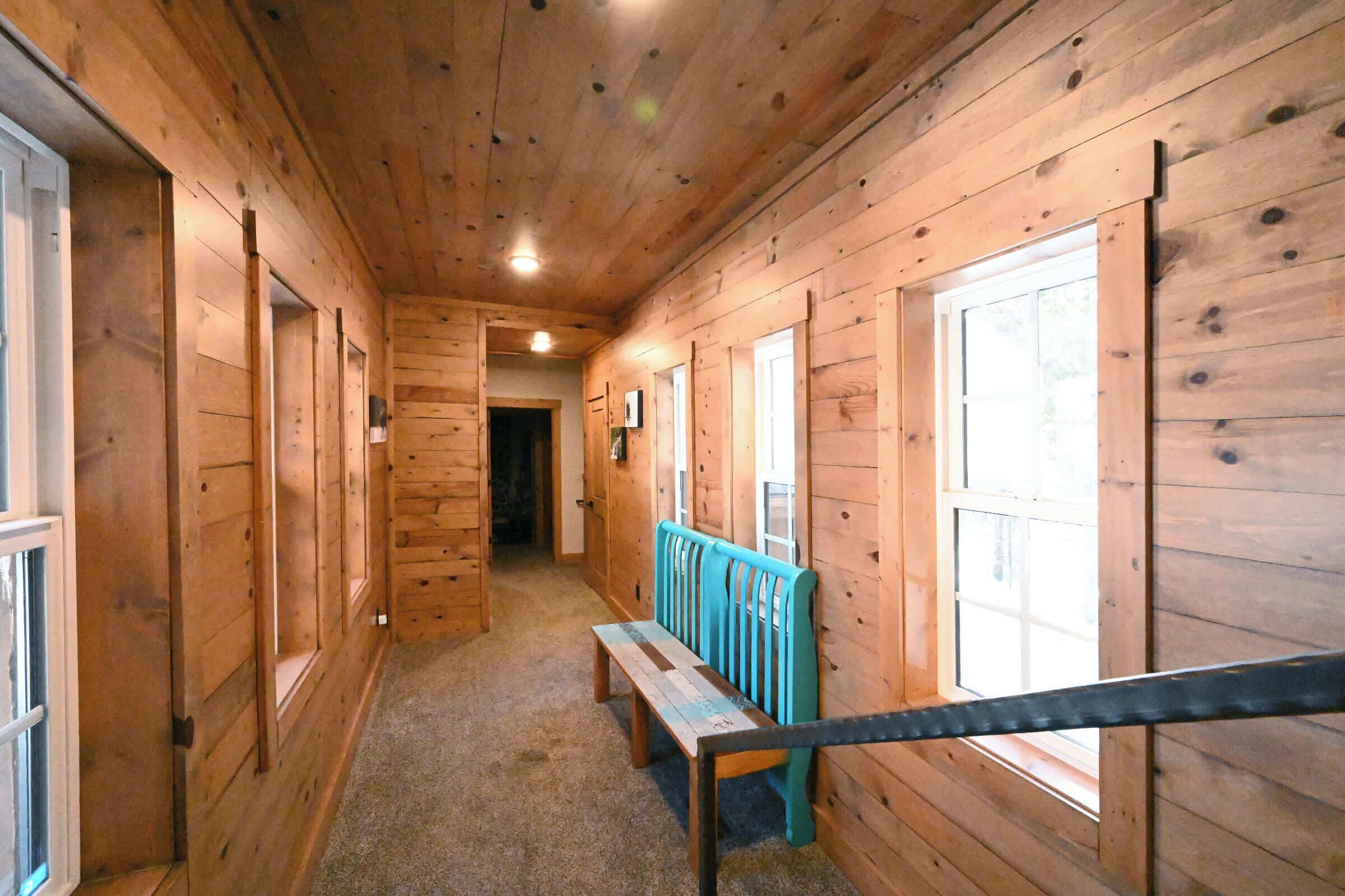 A wooden hallway with benches and windows.