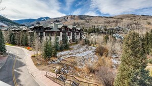 A lodge with a ski slope in the background, surrounded by mountains and trees.