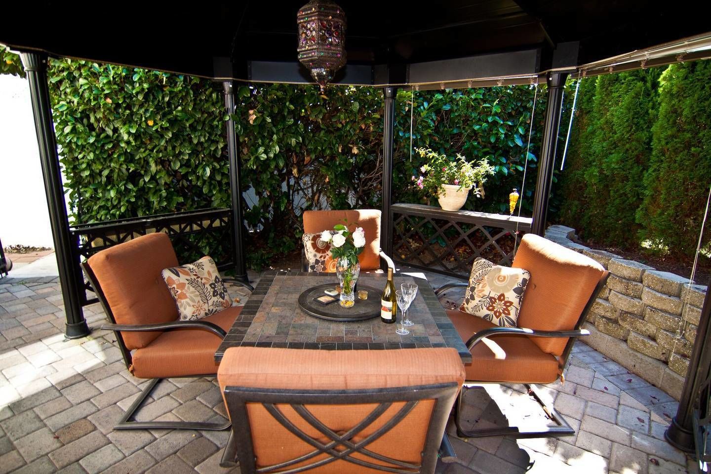 Un espacio de estar al aire libre cubierto con una mesa, sillas y un farol decorativo.