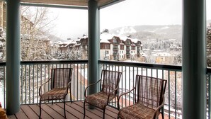 A balcony with wicker chairs and a view of snow-covered buildings.