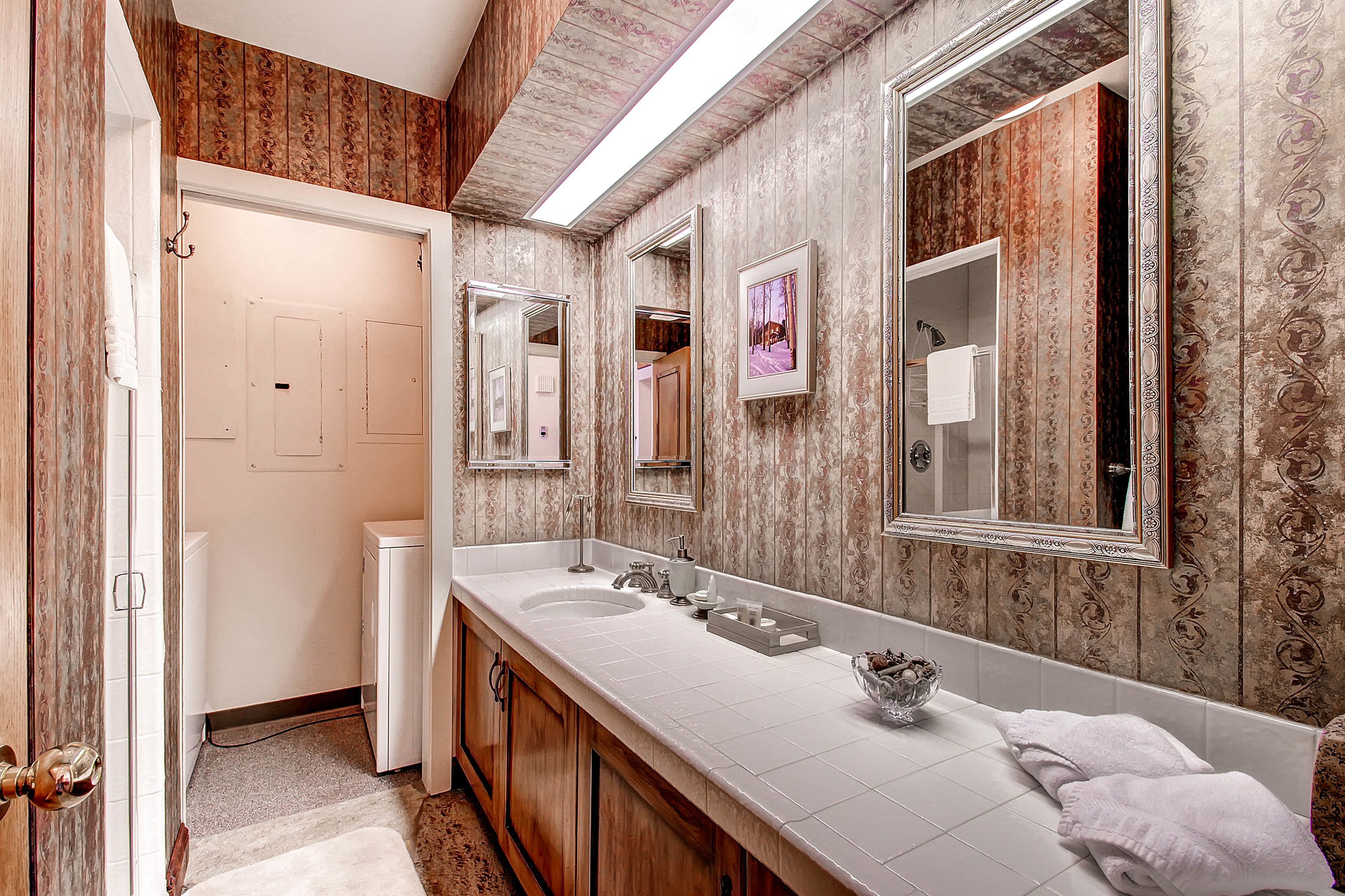 A bathroom with a wooden vanity, two sinks, a large mirror, and a shower area.