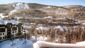 Ein schneebedecktes Resort mit mehreren Gebäuden, darunter eine große Lodge mit Balkonen und ein kleineres Gebäude mit einem verschneiten Dach.