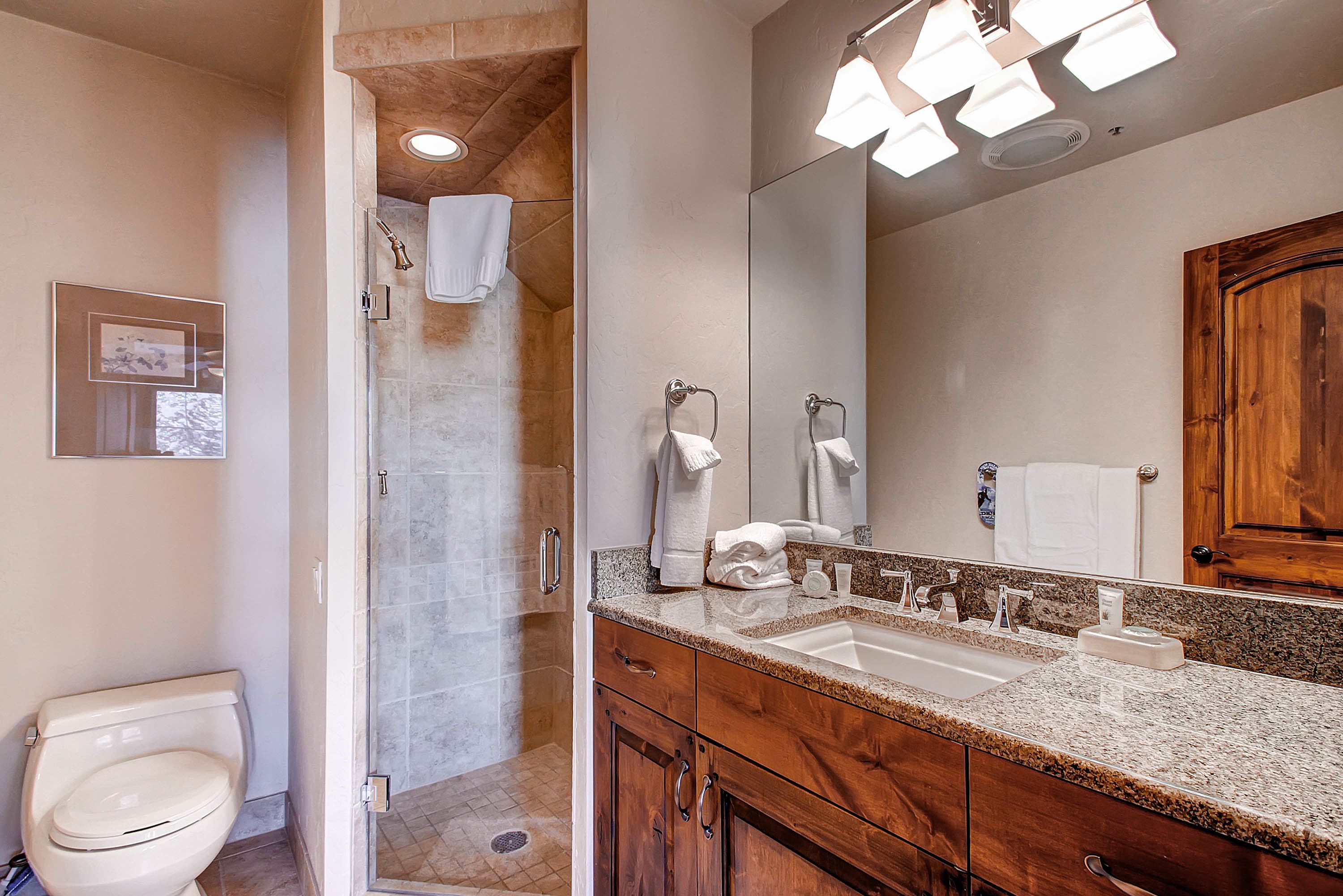 Un baño moderno con ducha, inodoro y tocador con un espejo grande.