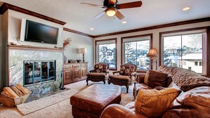 A living room with a fireplace, leather furniture, and a television on the wall. - Centennial 2 Bedroom Condo Unit no. 3 (Avon)