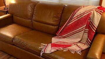 A brown leather sofa with a red and white patterned throw blanket draped over it.