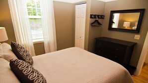 A bedroom with a bed, a dresser, a mirror, and a door. - Lori Lanes 'romeo Cottage' ~ 2 Bedroom ~ Downtown (Ashland)