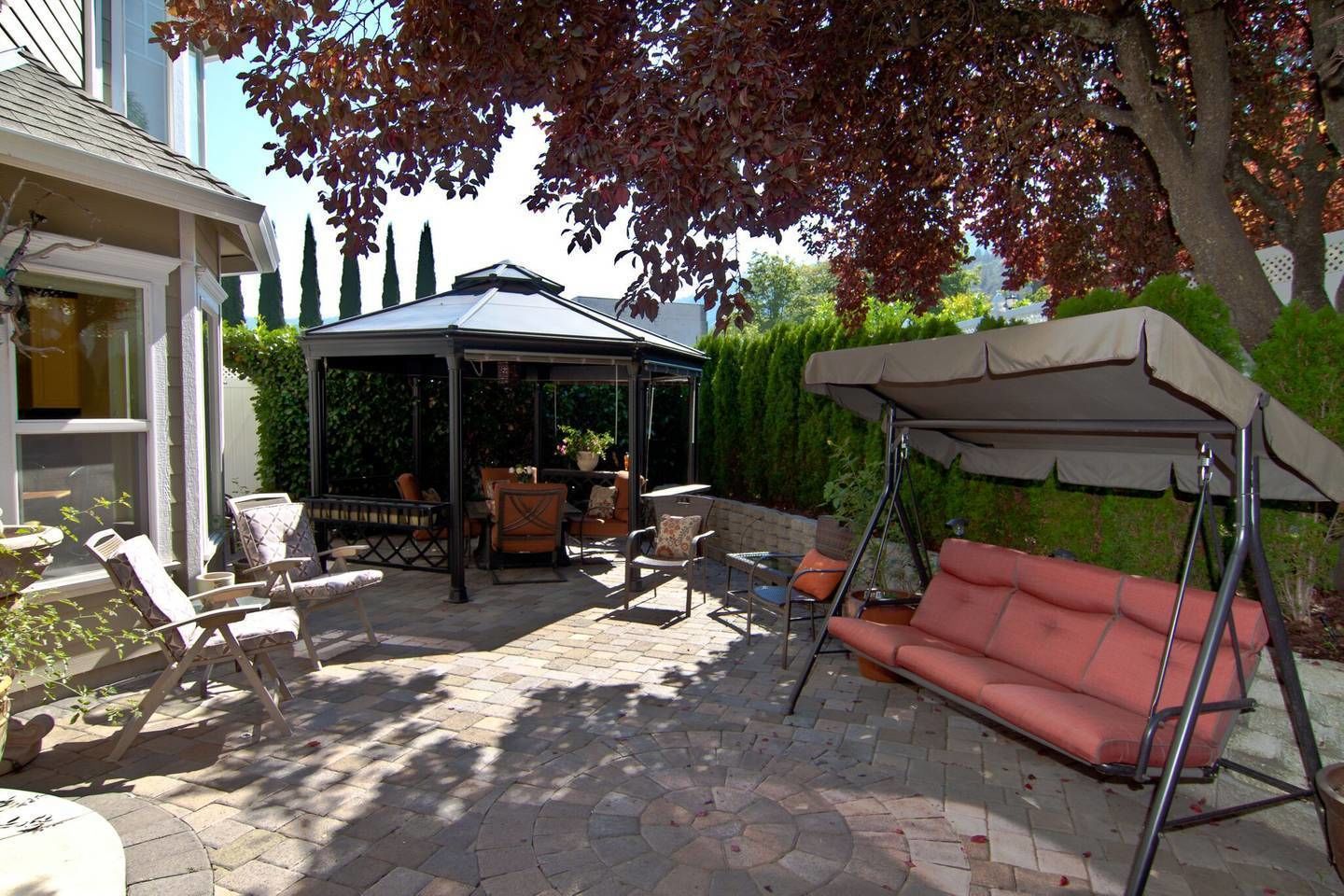Un patio con una zona de estar techada, una hamaca y un pérgola.