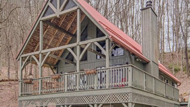 Eine zweistöckige Holzhütte mit Balkon, Schornstein und einer Veranda.