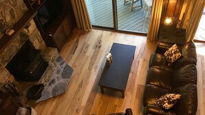 Ein gemütliches Wohnzimmer mit Kamin aus Stein, einer Ledersofa und einem Holztisch.