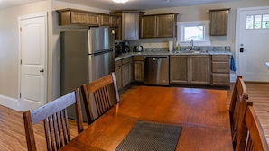 Una cocina moderna con armarios de madera, electrodomésticos de acero inoxidable y un comedor con mesa y sillas de madera.