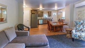 Un espacio habitable compacto con sofá, mesa de comedor, sillas y una zona de cocina.