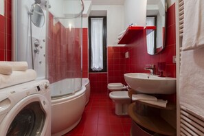 A bathroom with a washing machine, a bathtub, a toilet, and a sink.