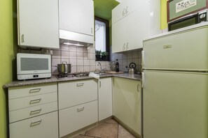 Een keuken met witte kastjes, een fornuis, een magnetron en een koelkast.