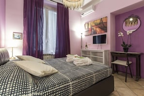 A bedroom with a bed, a TV, a desk, and a chair.