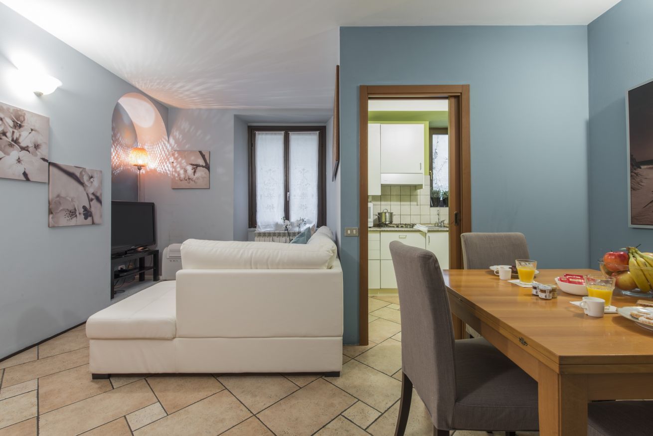 Ein modernes Wohnzimmer mit einer Couch, einem Esstisch mit Stühlen, einem Fernseher und Kunstwerken an den Wänden.