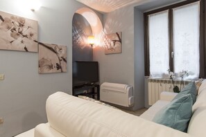 Een woonkamer met een bank, een flatscreen-tv, een radiator en wanddecoratie.