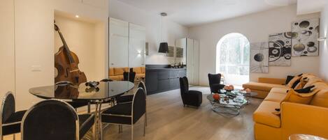 A modern living room with a dining area, a kitchen, and a large window.