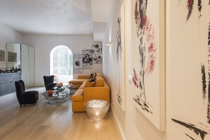 A modern living room with a sofa, a coffee table, and a dining area with chairs.