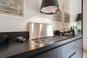 Une cuisine moderne dotée d’une hotte en acier inoxydable, d’un plan de travail noir et d’objets décoratifs, notamment une maquette de voiture et des bouteilles de vin.