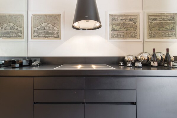 Una cocina moderna con una isla central, iluminación colgante y cuadros en las paredes.